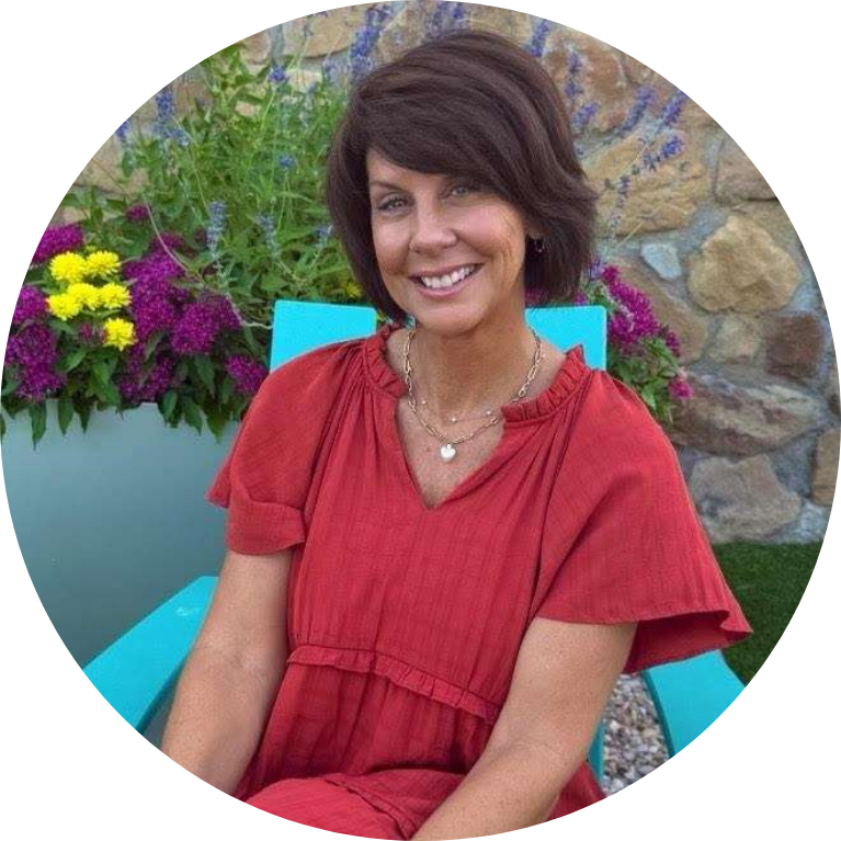 Patty, patient coordinator- portrait smiling sitting in Adirondack chair in garden